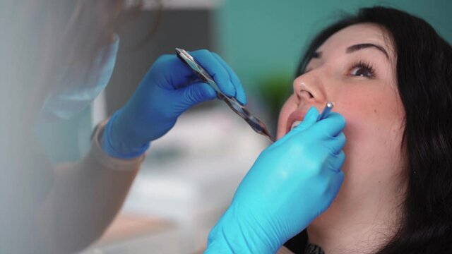 Close-up process of brushing teeth in dental clinic. A professional dentist treats teeth with a special instrument for female patient. Working process in dentistry. Healthcare and medicine concept.