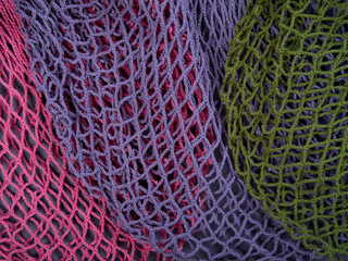 The multicolor background of the zero waste string bags, closeup of the knitted net. Selective focus.