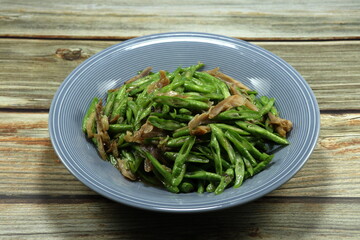 Traditional fried and stirred sliced green bean (Yardlong bean) mixed with chopped chicken serving on the plate. 