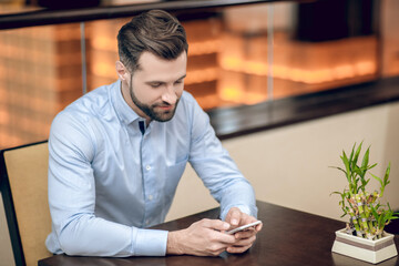 Young bearded man sitting at the table and waiting
