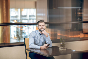 Young bearded man sitting at the table and waiting