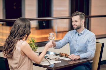 A couple having a dinner at the resaurant and saying a toast