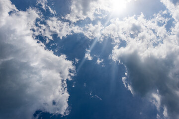Beautiful blue sky with white cumulus clouds and sun rays. Backlight photography.