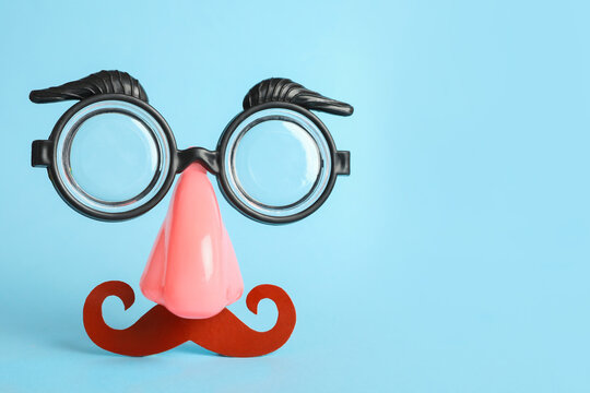 Funny face made with clown's accessories on light blue background, space for text