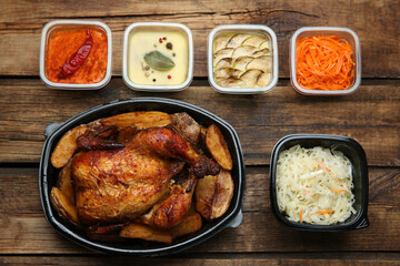 Plastic containers with different dishes on wooden table, flat lay. Food delivery service