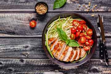 Fried chicken fillet and fresh vegetable salad of tomatoes, zucchini and pine nuts.