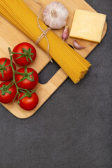 Spaghetti with ingredients for cooking pasta on grey background, top view. Flat lay, copy space