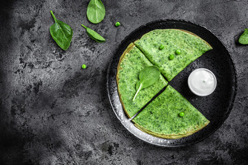 Spinach green pancakes crepes with sour cream. Healthy breakfast, vegetarian food, banner, menu recipe place for text, top view