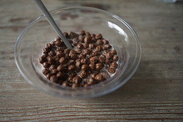 chocolate cereal in glass bowl on wooden background