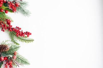 Christmas card, spruce twigs, red berries and cones, sprinkled with snow, on a white background, copy space