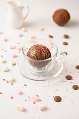 Cocoa bomb that melts with hot milk. Cup of dark hot chocolate. Comfort food. White wood table with green cloth and christmas decor. Great for cold season.