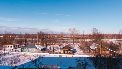 Fototapeta na wymiar The countryside in winter weather, blue clear skies, railway tracks, view from above, visible private houses, village life, village in winter.