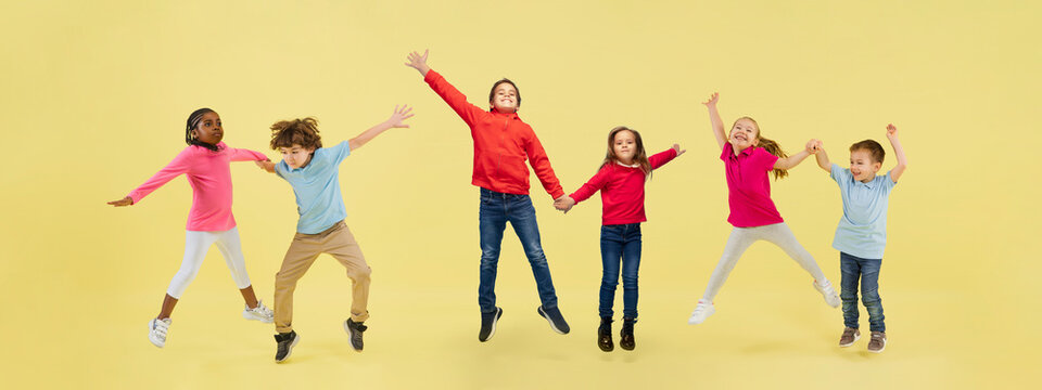 Little and happy kids gesturing isolated on yellow studio background. Human emotions, facial expression concept