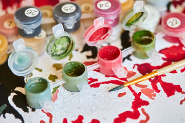 Acrylic paints with small brush on numbered canvas. Picture by numbers. Creative hobby. Painting for beginners.