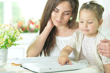 little cute girl  with mother reading book  at home