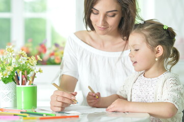 cute girl with mother drawing at the table