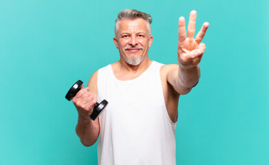 senior athlete man smiling and looking friendly, showing number three or third with hand forward,...