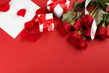 Flat lay composition with beautiful roses and gift boxes on red background, space for text. Valentine's Day celebration