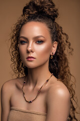 beautiful woman with delicate nude makeup and curly hair. luxury jewelry.