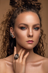 beautiful woman with delicate nude makeup and curly hair. luxury jewelry.