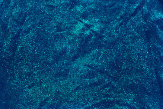 Spotted, crumpled, glowing background. Blue texture.