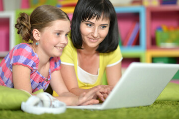 portrait of smiling   mother and daughter using laptop