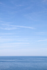 Naklejka na ściany i meble Blue sea and blue sky with wispy white clouds 