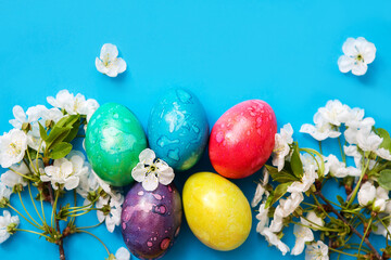 Fototapeta na wymiar Five colorful easter eggs and flowers on blue background.