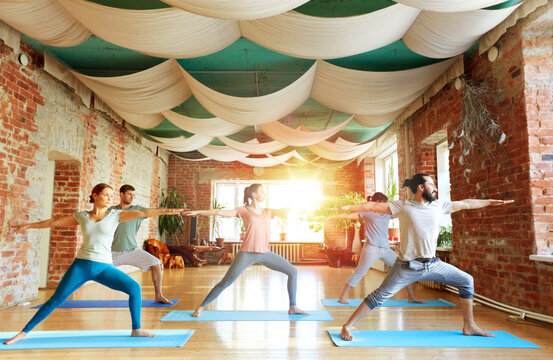 group of people doing yoga warrior pose at studio