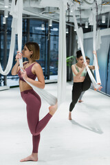 Young fit woman training with hanging hammock during fly yoga