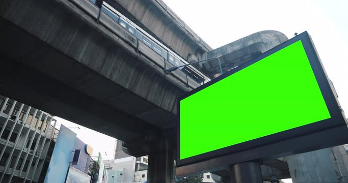 Empty modern billboard with a green screen for advertising with sky train moving forward in station, blank billboard on Electric train station in cyberpunk urban city.