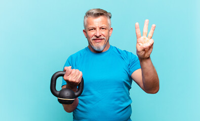 senior athlete man smiling and looking friendly, showing number three or third with hand forward,...