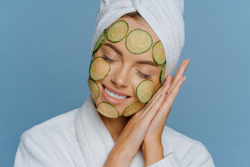 Relaxed satisfied woman tilts head on palms pressed together keeps eyes shut and smiles gently...