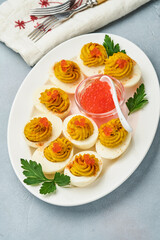 Stuffed eggs with red caviar and paprika on plate for appetizer easter table, top view, copy space. Traditional dish for Happy Easter holiday.