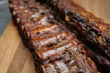 Tasty grilled pork ribs on wooden board, closeup