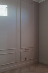 Close up view of modern and bright corner of empty cream room with ray of sunlight on wall and herringbone parquet floor