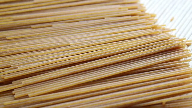Wholewheat spaghetti uncooked pasta on the table, close up view of raw diet macaroni