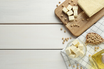 Cut tofu and soya beans on white wooden table, flat lay. Space for text