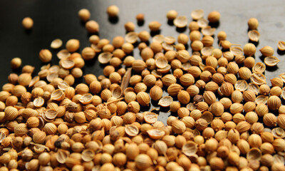 Coriander herb seeds on the black background, pile of dry spice, top view
