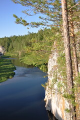 Landscape old cliff , blue river, blue sky and pine trees with forest.
