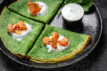 Green vegan crepes with spinach, smoked salmon and yogurt sauce, Healthy breakfast, vegetarian food, top view