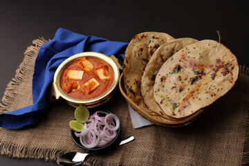 Paneer Butter Masala or Cheese Cottage Curry in serving a bowl or pan, served with naan or tandoori roti
