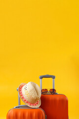 Summer time concept. Close up of two travel bags suitcases, straw hat and sunglasses on yellow...