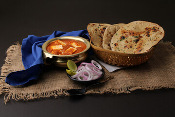 Paneer Butter Masala or Cheese Cottage Curry in serving a bowl or pan, served with naan or tandoori roti
