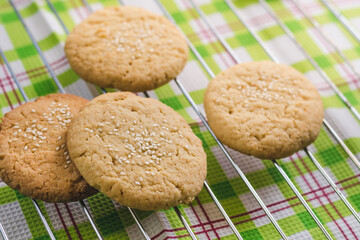 Homemade round shortbread cookies with sesame seeds on a wire rack