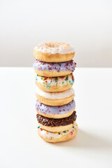 Looking stunning. Tower of various sweet colorful donuts with sprinkles and glaze isolated over light background