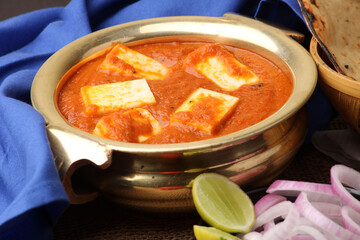 Paneer Butter Masala or Cheese Cottage Curry in serving a bowl or pan, served with naan or tandoori roti
