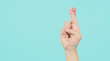 Hand is do goodluck hand sign and have foam soap bubbles on a green mint or Tiffany Blue isolated background