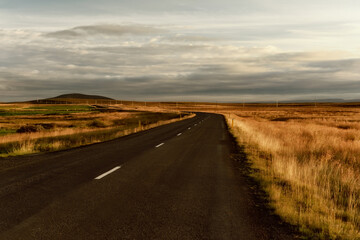 Fototapeta na wymiar a deserted asphalt road running away into the hills. Iceland. The spirit of travel and adventure. 