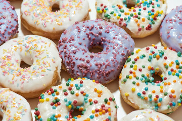 Sugary food. Close up shot of assorted round glazed donuts with colorful sprinkles, top view
